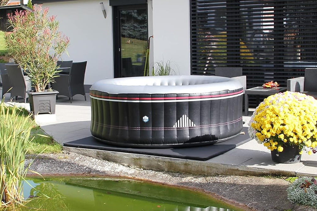 Hot tub in a garden setting with a pond and outdoor furniture.