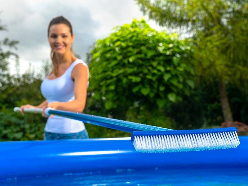 Woman cleaning a pool with a blue brush