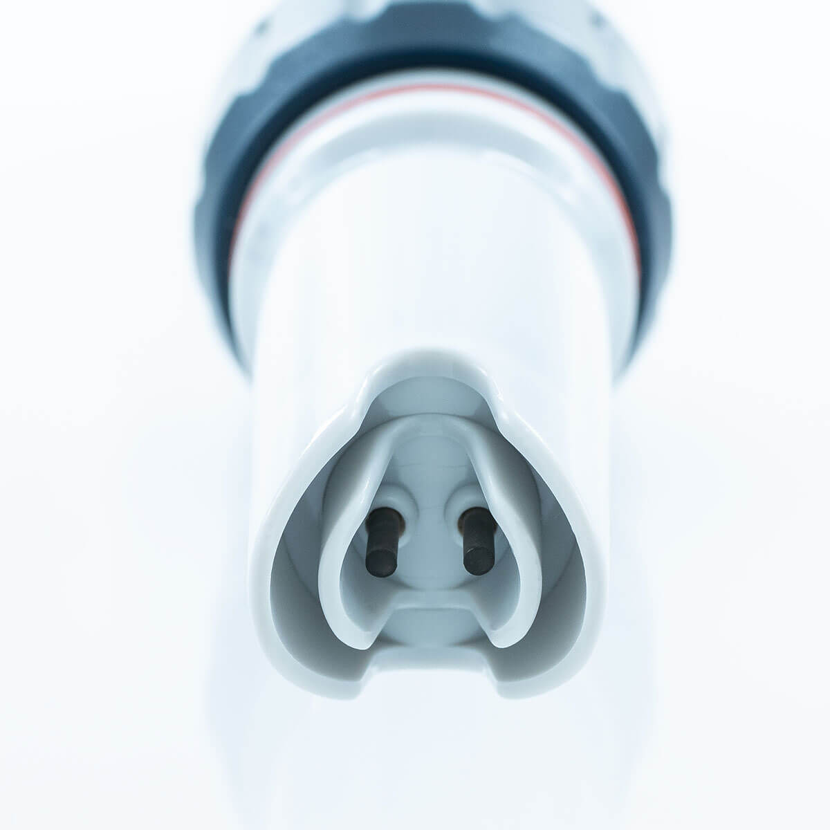 Close-up of a white electrical connector plug with two dark pins visible in the center, set against a bright white background.