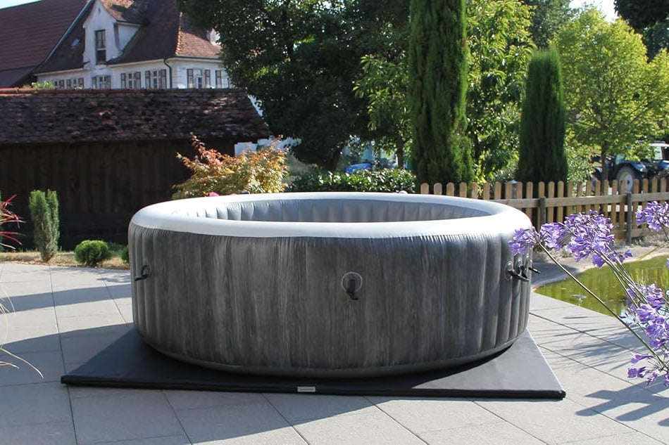 Inflatable hot tub on a leather mat with garden and house in the background