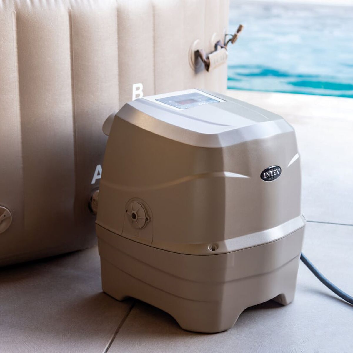 Intex hot tub pump on a tiled floor with water and pool equipment in the background