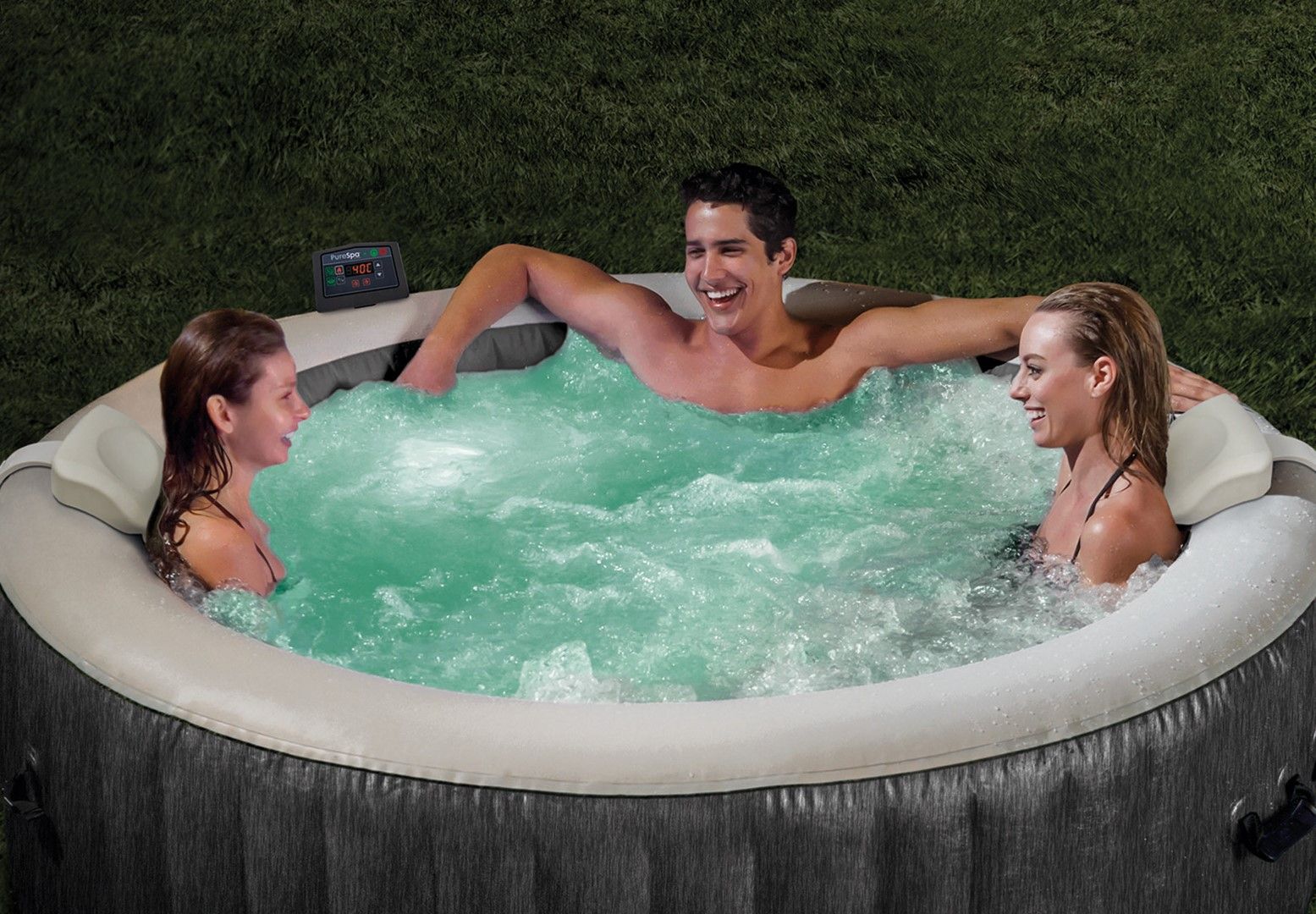 Three people in a hot tub with green water, surrounded by grass.