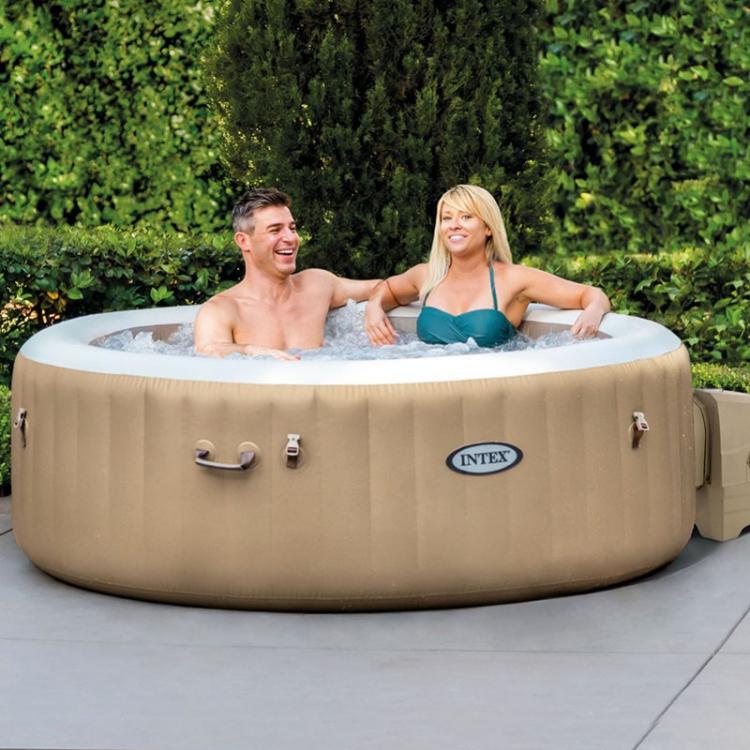 Two people in an inflatable hot tub with Intex branding, surrounded by greenery.