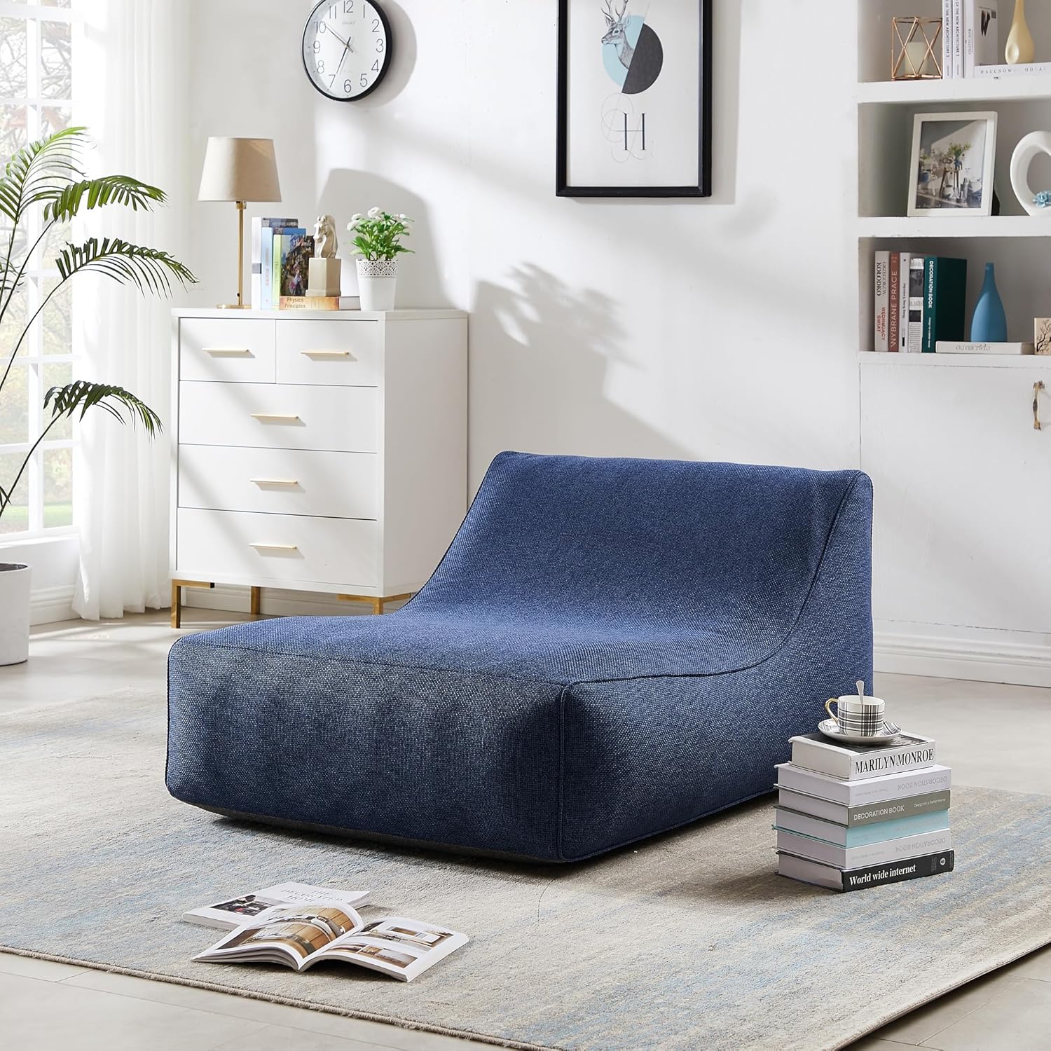 Blue lounge chair in a modern living room with white furniture and decor.